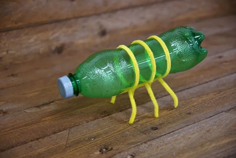 An old bottle on it's side, with pipe cleaners made into legs